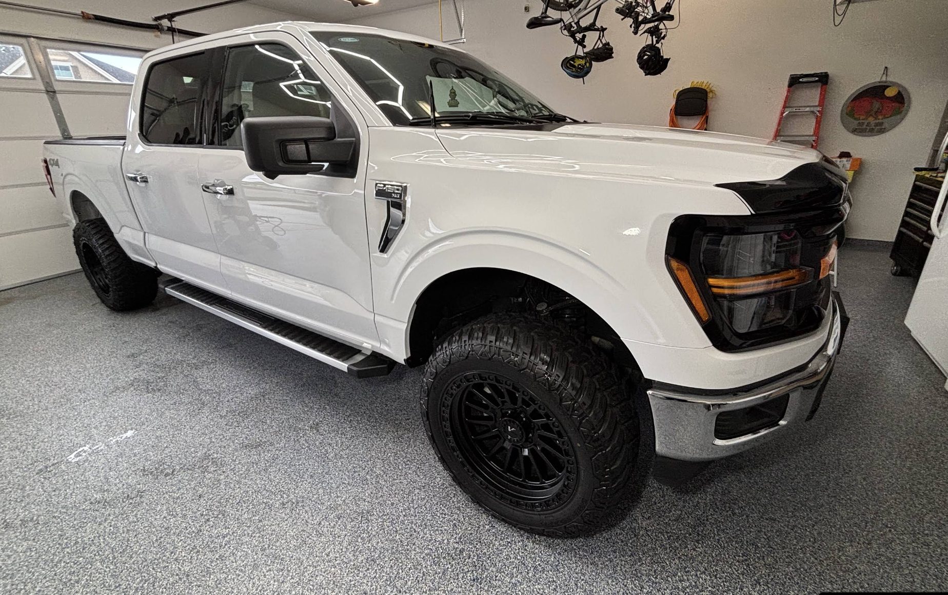 White Ford F-150 XLT detailed inside a garage with polished wheels and glass